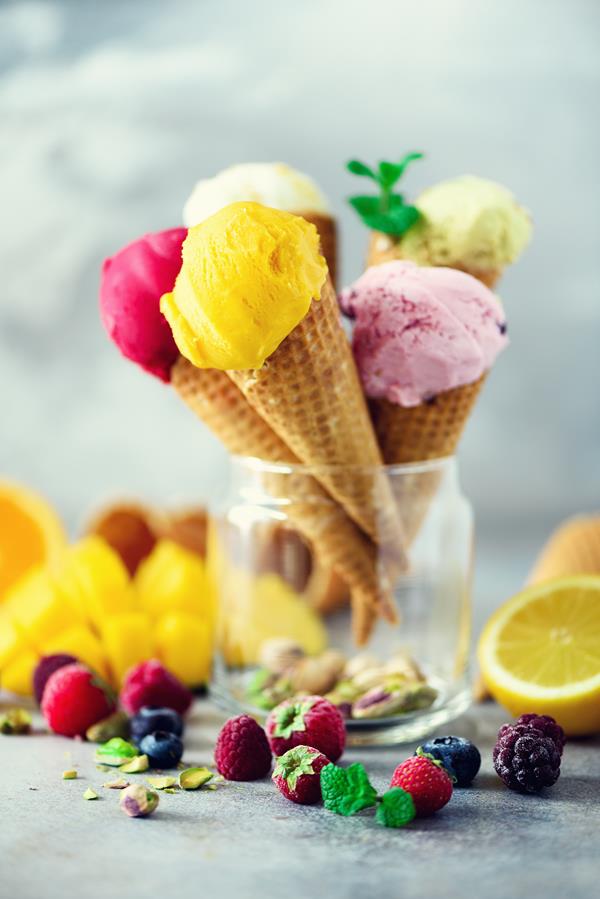 Colorful ice cream balls in waffle cones with different flavors - mango, lime, mint, pistachio, orange, strawberries, raspberries, blueberries. Summer concept. S